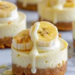 Mini banana pudding cheesecakes topped with whipped cream and banana slices