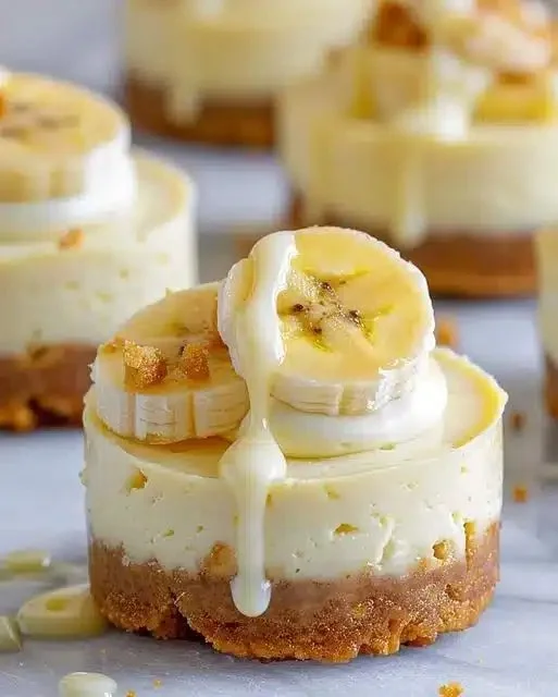 Mini banana pudding cheesecakes topped with whipped cream and banana slices