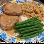 Smothered pork chops with Rice A Roni and green beans on a plate