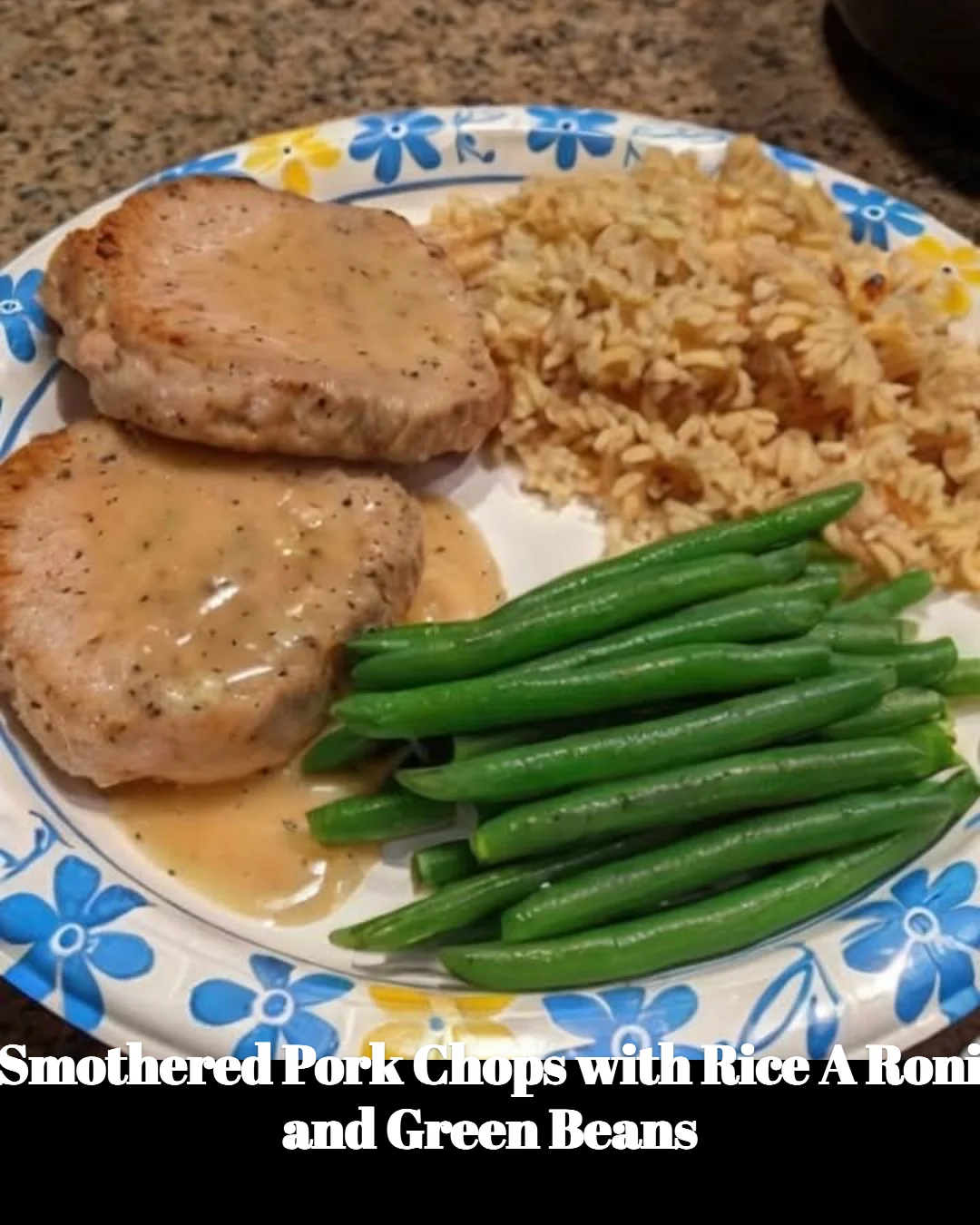 Smothered pork chops with Rice A Roni and green beans on a plate
