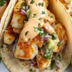Zesty fish tacos garnished with spicy Sriracha lime sauce and fresh ingredients.