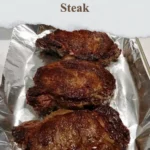 Cooked ribeye steak served on a plate with herbs and spices.